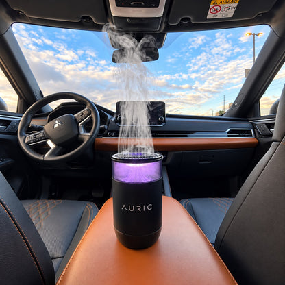 Difusor AURIC® LUXURY con luz violeta liberando vapor en el interior del auto